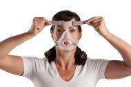 Пациентка със сънна апнея поставя CPAP маска на лицето си. 